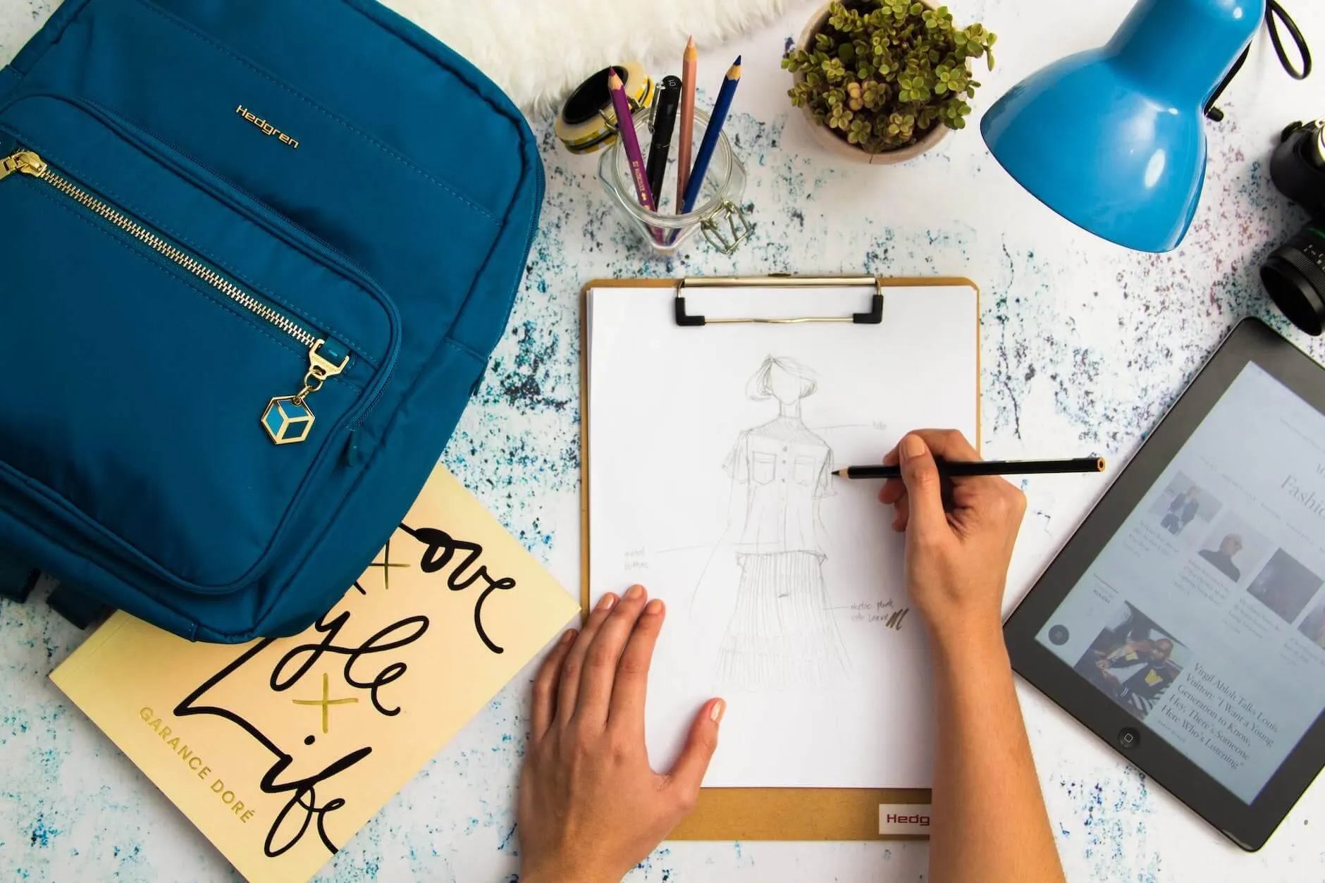 Designer sketching a figure on a clipboard next to a tablet