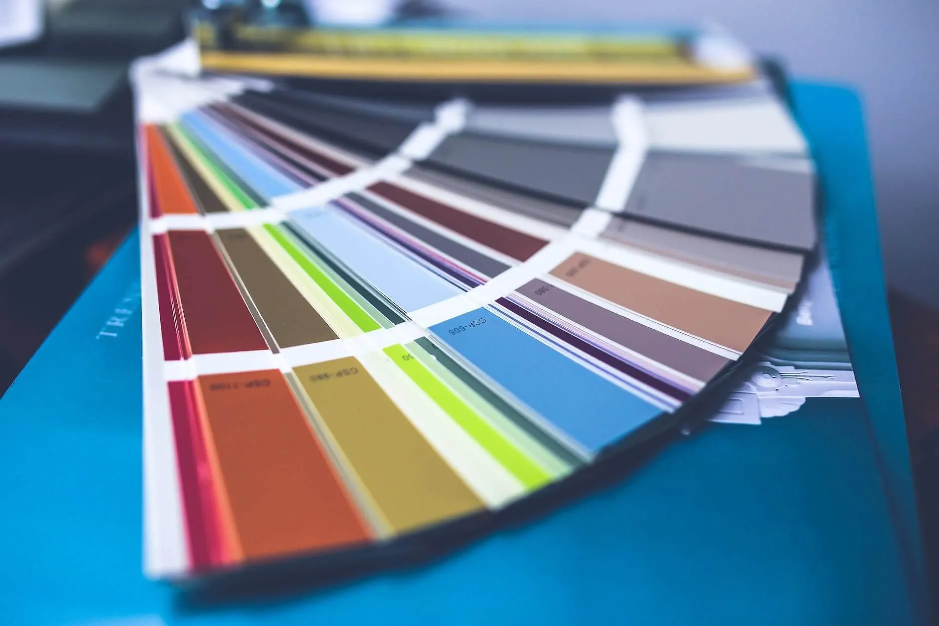 Fan of printed colour swatches on a blue desk